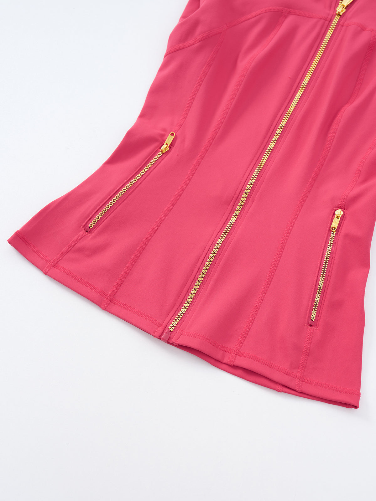 A close-up of a bright pink sleeveless top or dress with gold-tone zippers, including a central front zipper and two side zip pockets, shown on a clean white background.