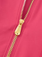 Close-up of a bright pink zippered garment with a shiny gold zipper pull and matching gold zipper teeth.