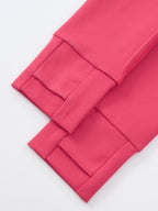 A close-up of bright pink fabric with folded cuffs and stitched panel details, photographed on a clean white background.